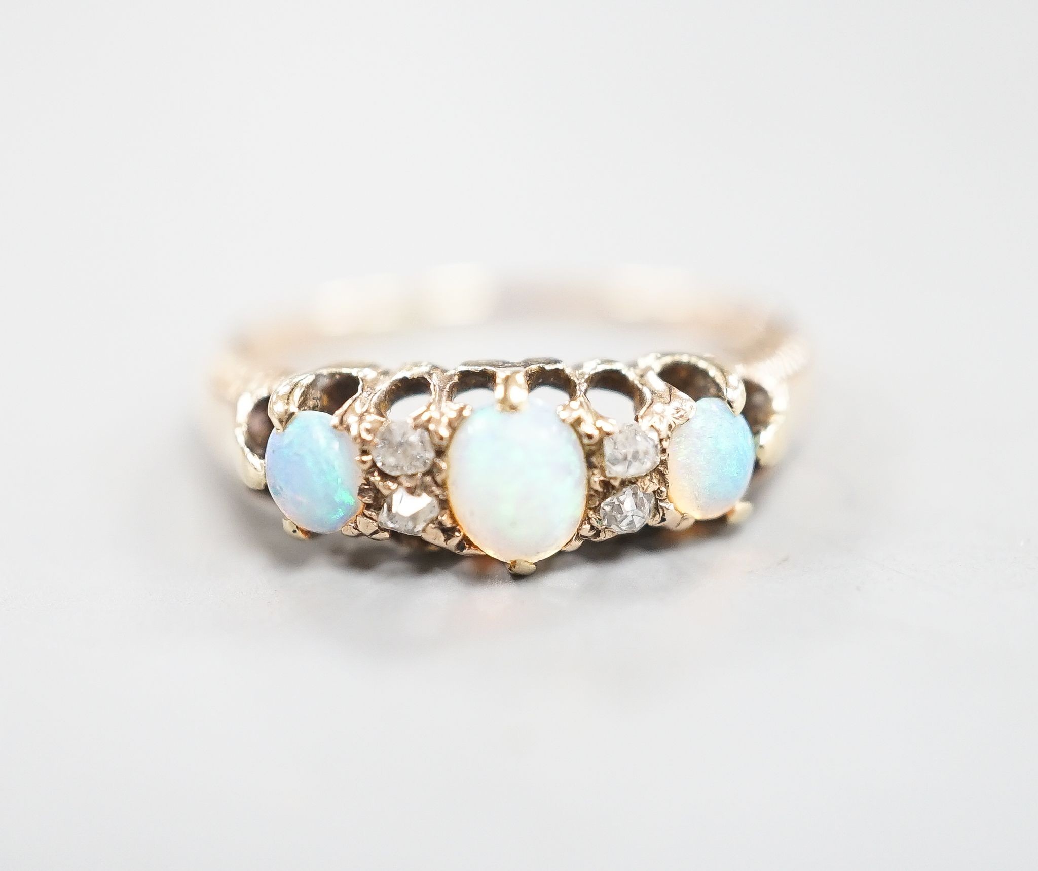 An early 20th century yellow metal three stone white opal and four stone diamond chip set half hoop ring, size M, gross weight 2.6 grams.